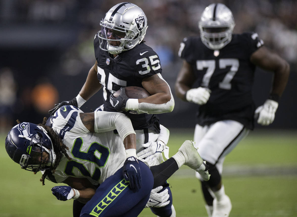 Raiders running back BJ Emmons (35) runs past Seattle Seahawks defensive back Ryan Neal (26) in ...