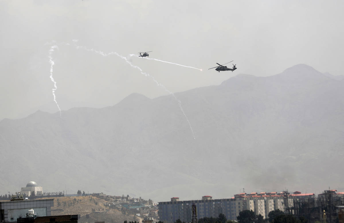 Anti-missile decoy flares are deployed as U.S. Black Hawk military helicopters fly over the cit ...
