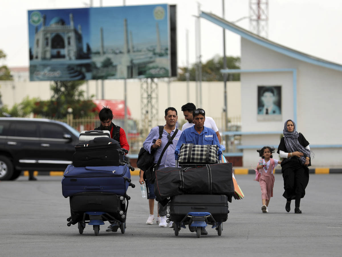 Passengers walk to the departures terminal of Hamid Karzai International Airport in Kabul, Afgh ...