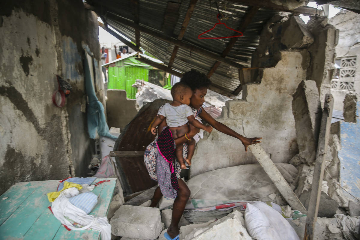 A woman carries her child as she walks in the remains of her home destroyed by Saturday´s ...