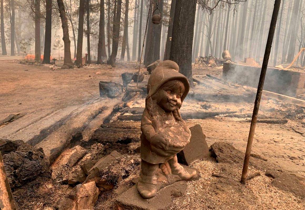 A surviving ceramic statue is seen outside a house that burned along North Arm Road in Plumas C ...