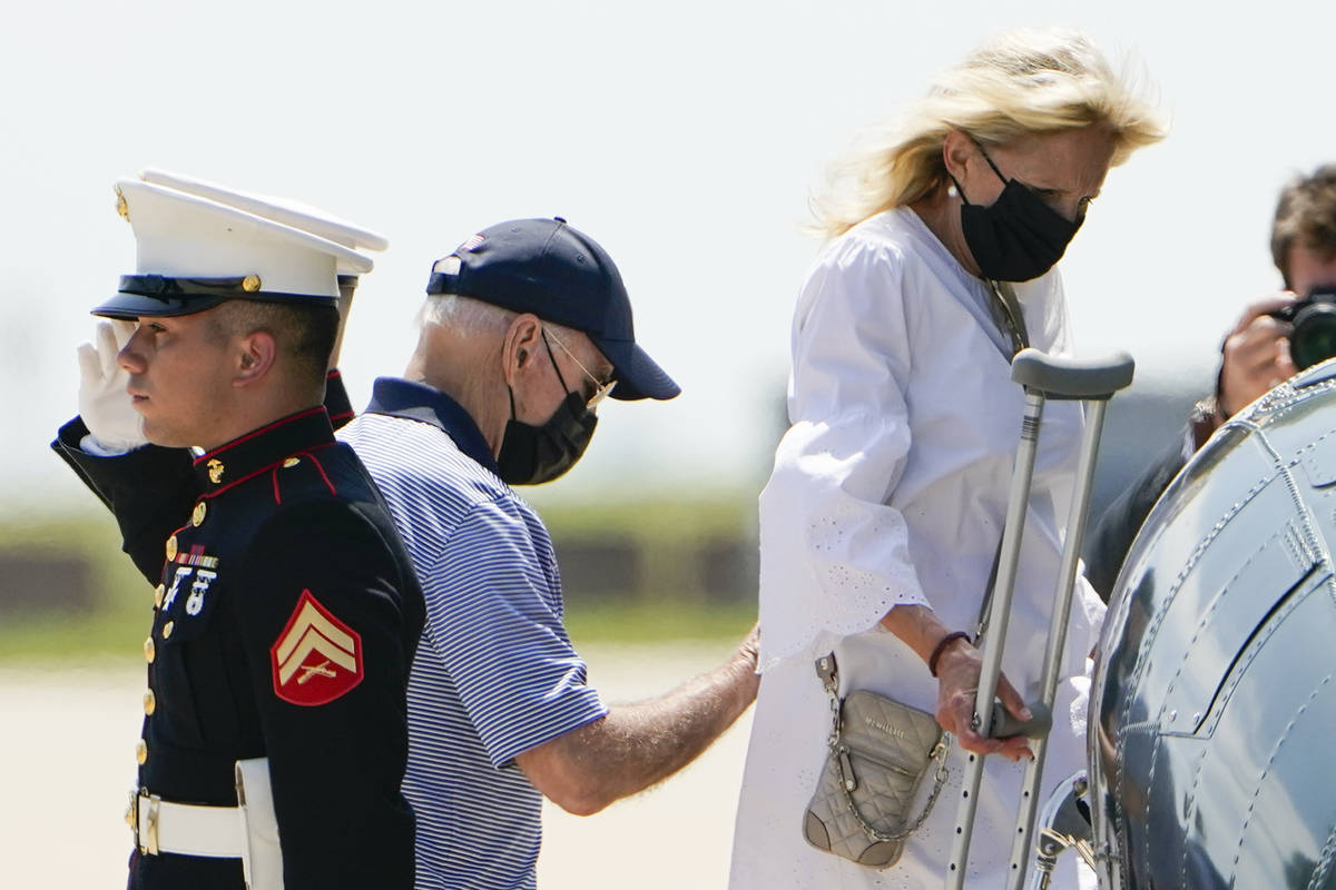 President Joe Biden helps first lady Jill Biden as they board Marine One to depart Delaware Air ...