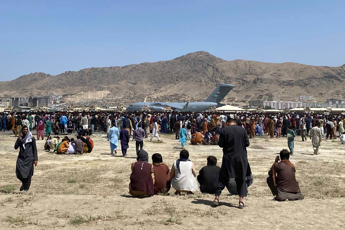 Hundreds of people gather near a U.S. Air Force C-17 transport plane at a perimeter at the inte ...