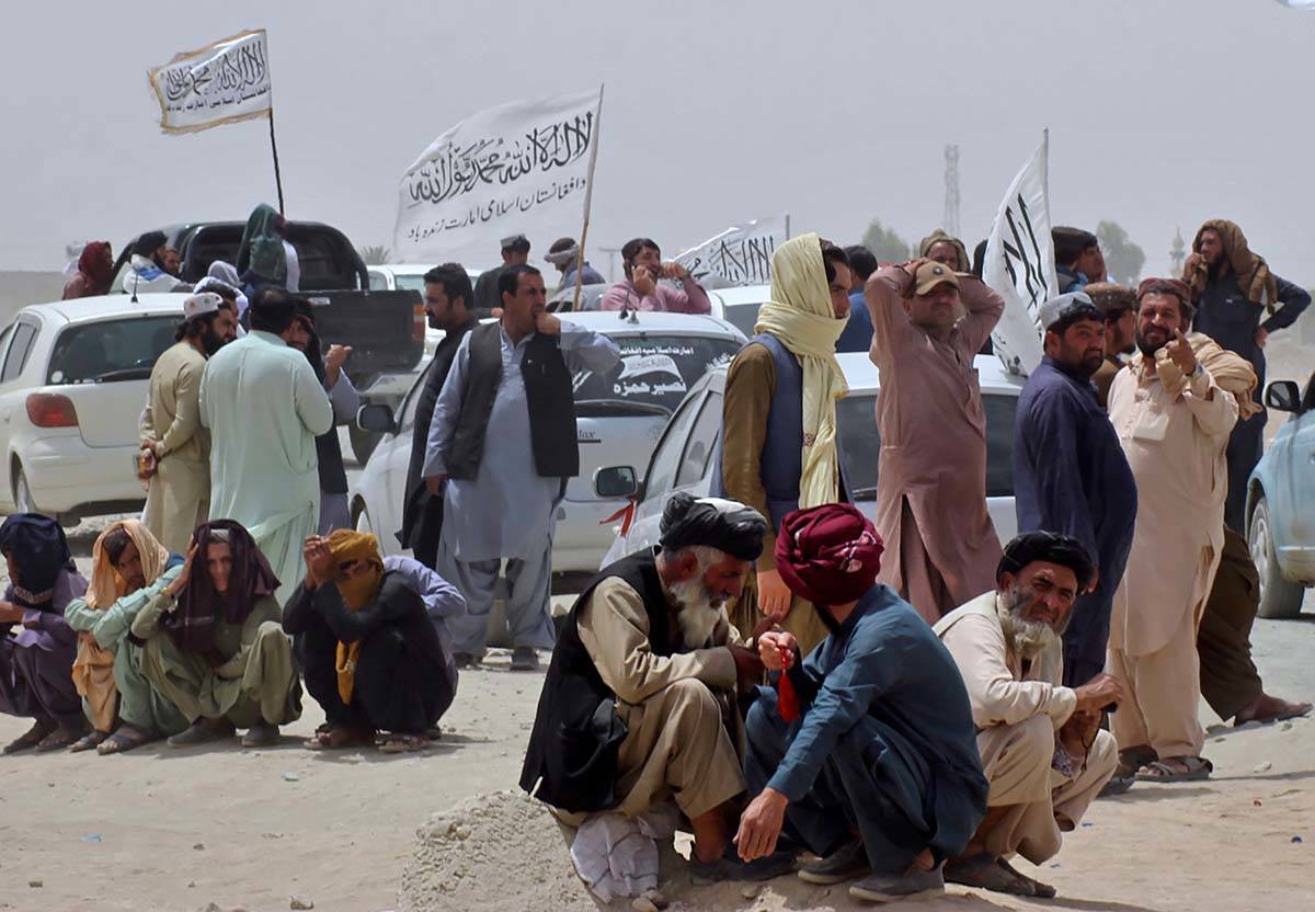 People near Taliban signature white flags wait for the arrival of their relatives, who were rep ...