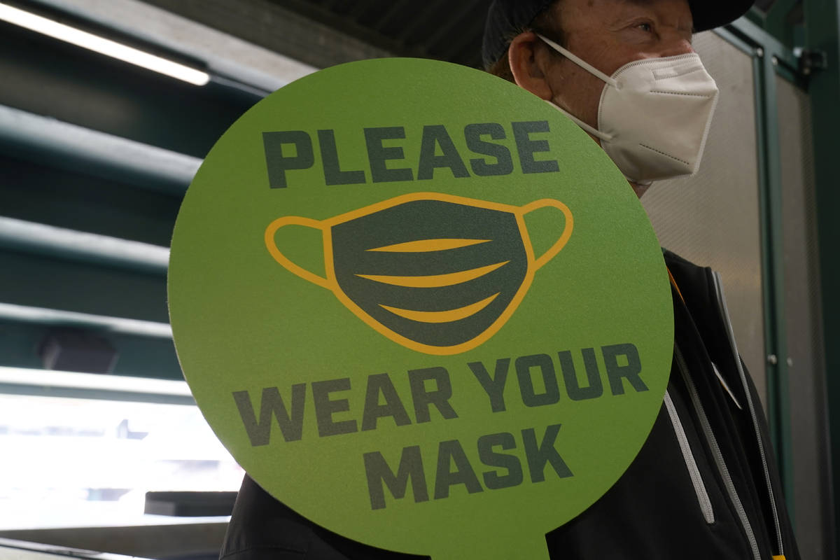 A stadium worker holds up a sign for people to wear face masks before a baseball game between t ...