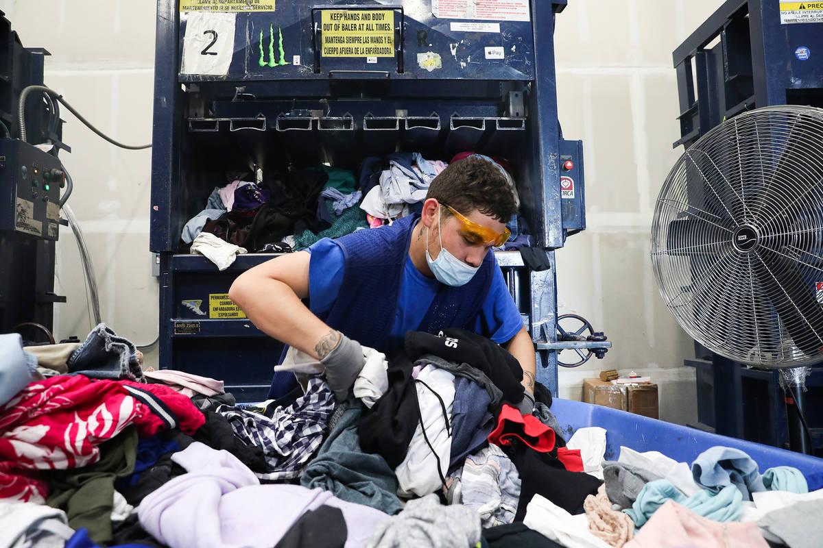 Steven Aragon picks up clothes to put in the baler at the warehouse at Goodwill Clearance Cente ...