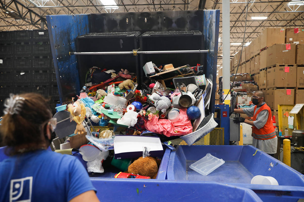 Jimmy Carrion tips donated product into a bin in the warehouse at the Goodwill Clearance Center ...