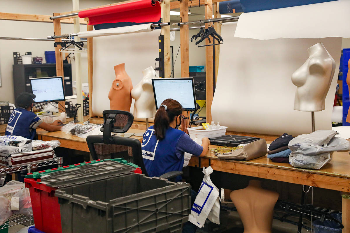 Workers list items online in the e-commerce area at the warehouse at the Goodwill Clearance Cen ...
