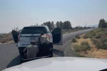 Nye County Sheriff's Office deputies take cover behind a patrol unit on Dana Way on Thursday, A ...