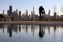 The Chicago skyline is reflected in the water of the thawed snow as a cyclist passes by at Nort ...