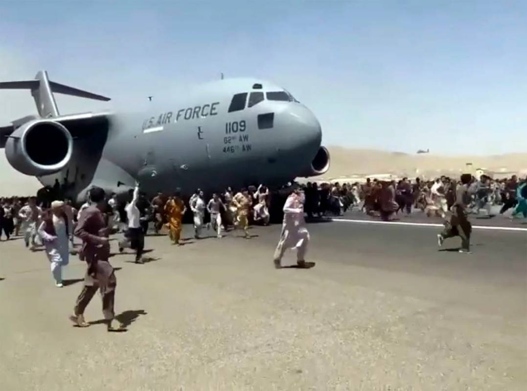Hundreds of people run alongside a U.S. Air Force C-17 transport plane as it moves down a runwa ...