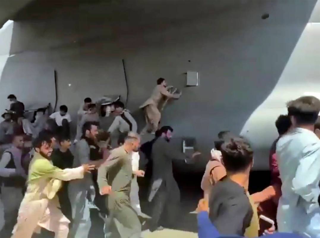 Hundreds of people run alongside a U.S. Air Force C-17 transport plane, some climbing on the pl ...