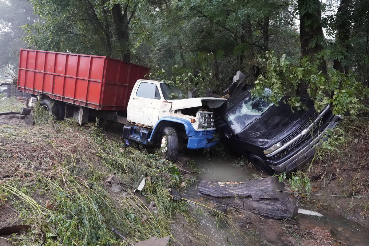 A truck and a car sit in a creek Sunday, Aug. 22, 2021, after they were washed away the day bef ...