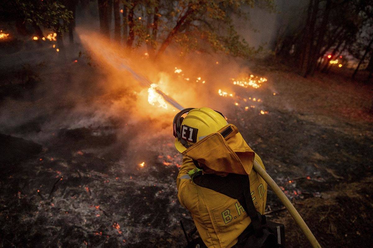 A firefighter hoses down flames from the Dixie Fire in Genesee, Calif., on Saturday, Aug. 21, 2 ...
