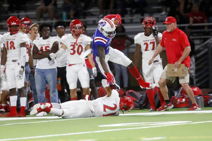 Liberty High School's Germie Bernard (2), center, jumps over Arbor View High School's Aiden Pow ...