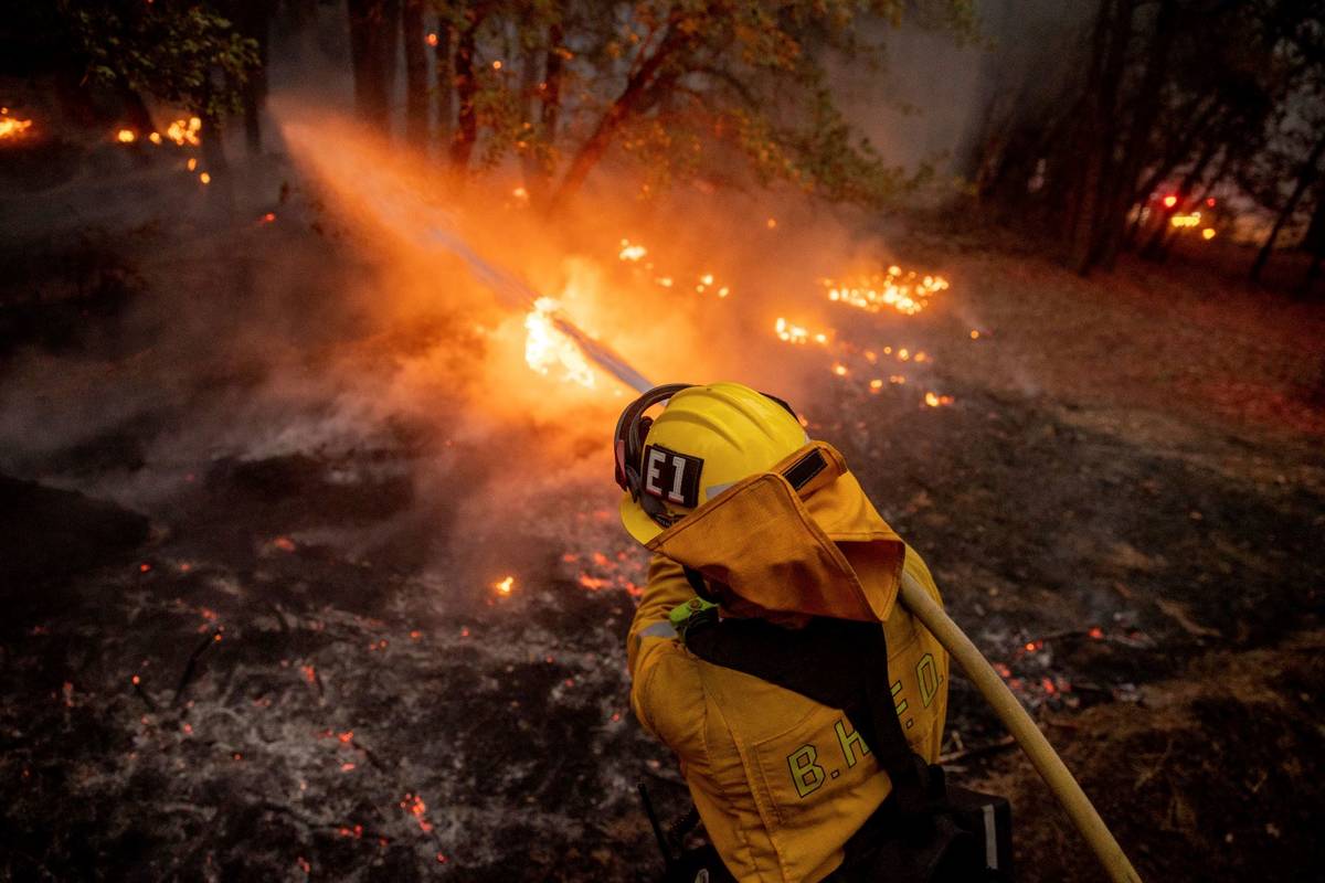 A firefighter hoses down flames from the Dixie Fire in Genesee, Calif., on Saturday, Aug. 21, 2 ...