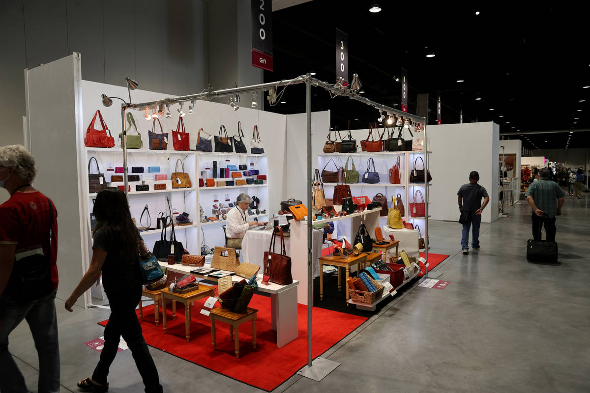 Conventioneers walk past the John Cole Collection/J.P. Ourse booth at the Las Vegas Market home ...