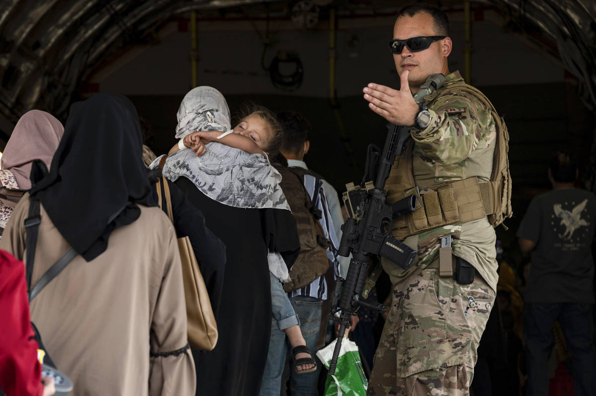 In this image provided by the U.S. Air Force, a U.S. Air Force Airman guides evacuees aboard a ...