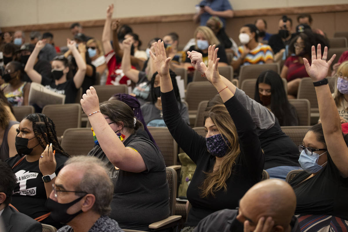People raise their hands to show support for a speaker's comments during a Clark County School ...