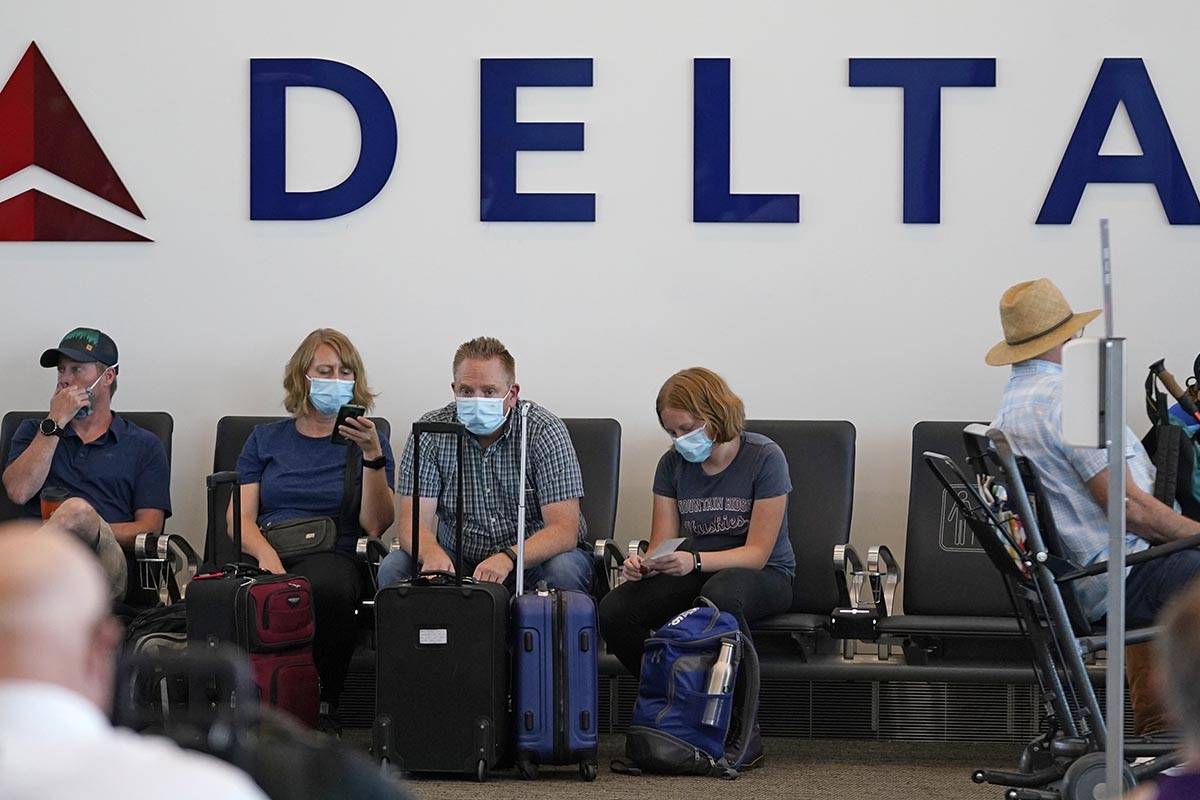 FILE - People sit under Delta sign at Salt Lake City International Airport on July 1, 2021, in ...