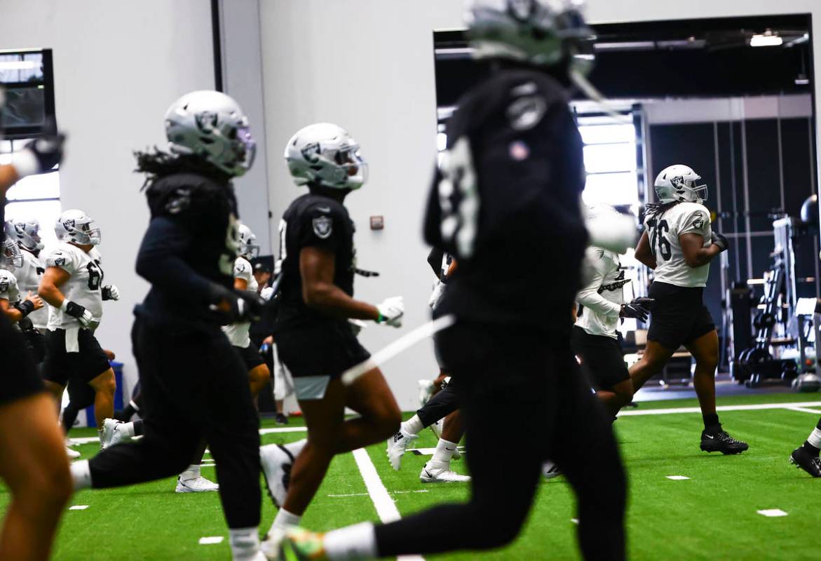 Raiders offensive guard John Simpson, far right, warms up with teammates during training camp a ...