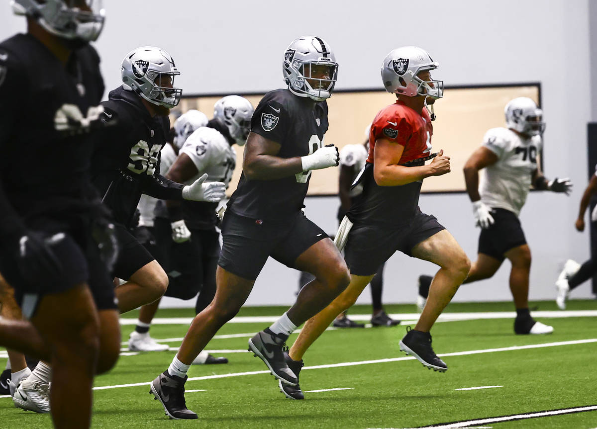 Raiders defensive end Yannick Ngakoue, left, and quarterback Derek Carr warm up during training ...
