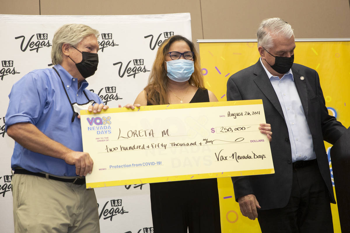 Loreta Mercado, center, poses for photos after winning $250,000 during the final Vax Nevada Day ...