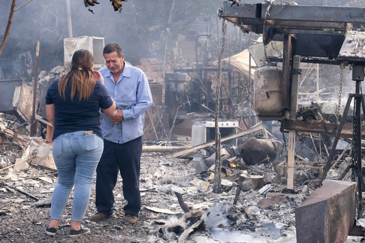 Homeowner Jose Lamas, right, and his daughter Astrid Covarrubias survey the charred debris left ...