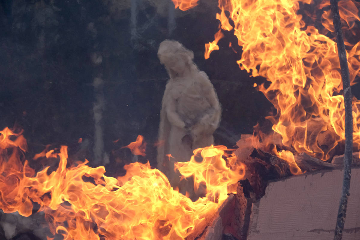 A sculpture is seen at a burning house as the South Fire burns in Lytle Creek, San Bernardino C ...