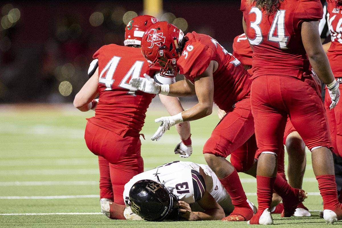 Arbor View's Marcus Young (36) looks over Faith Lutheran's Rylan Walter (13) after getting a ta ...
