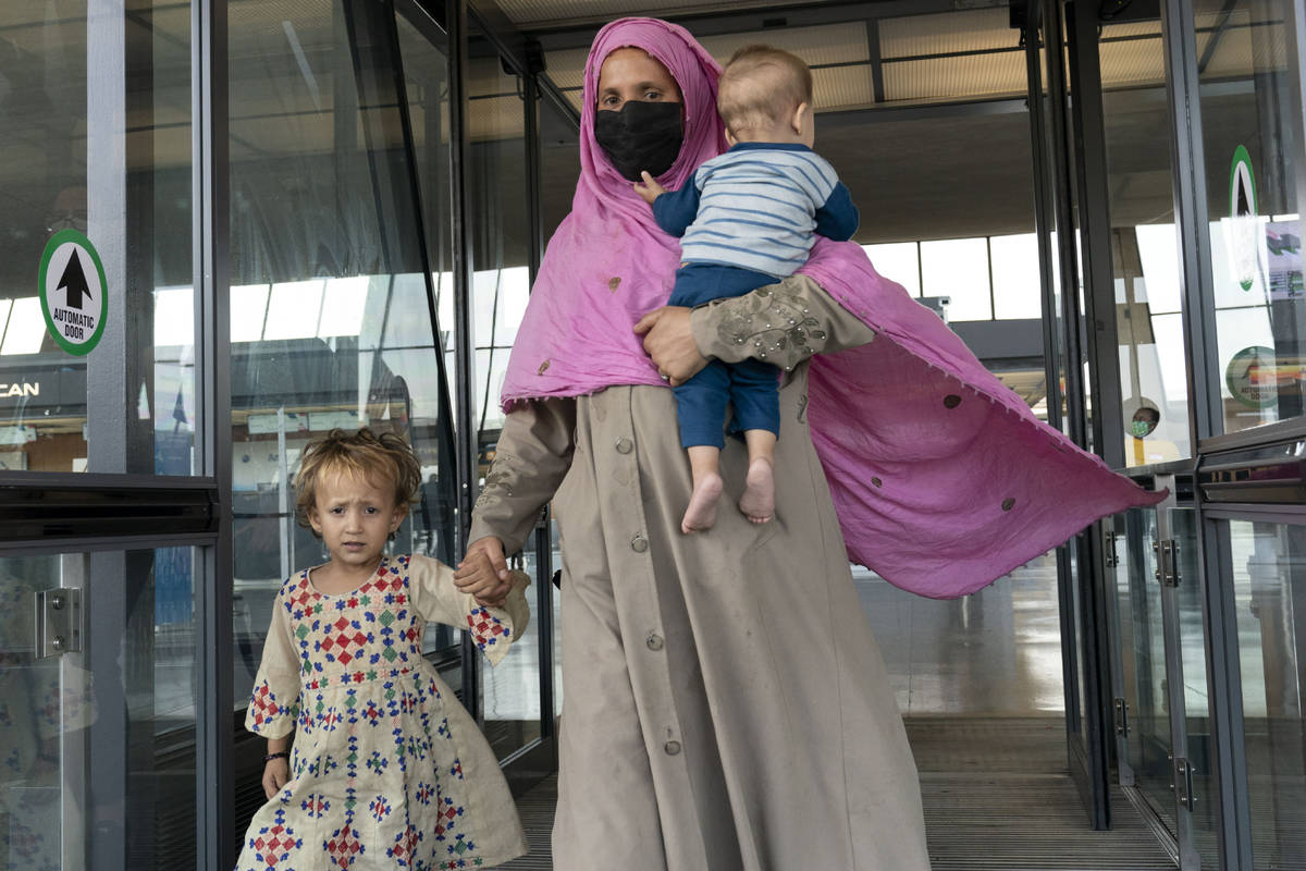 Families evacuated from Kabul, Afghanistan, walk through the terminal before boarding a bus aft ...