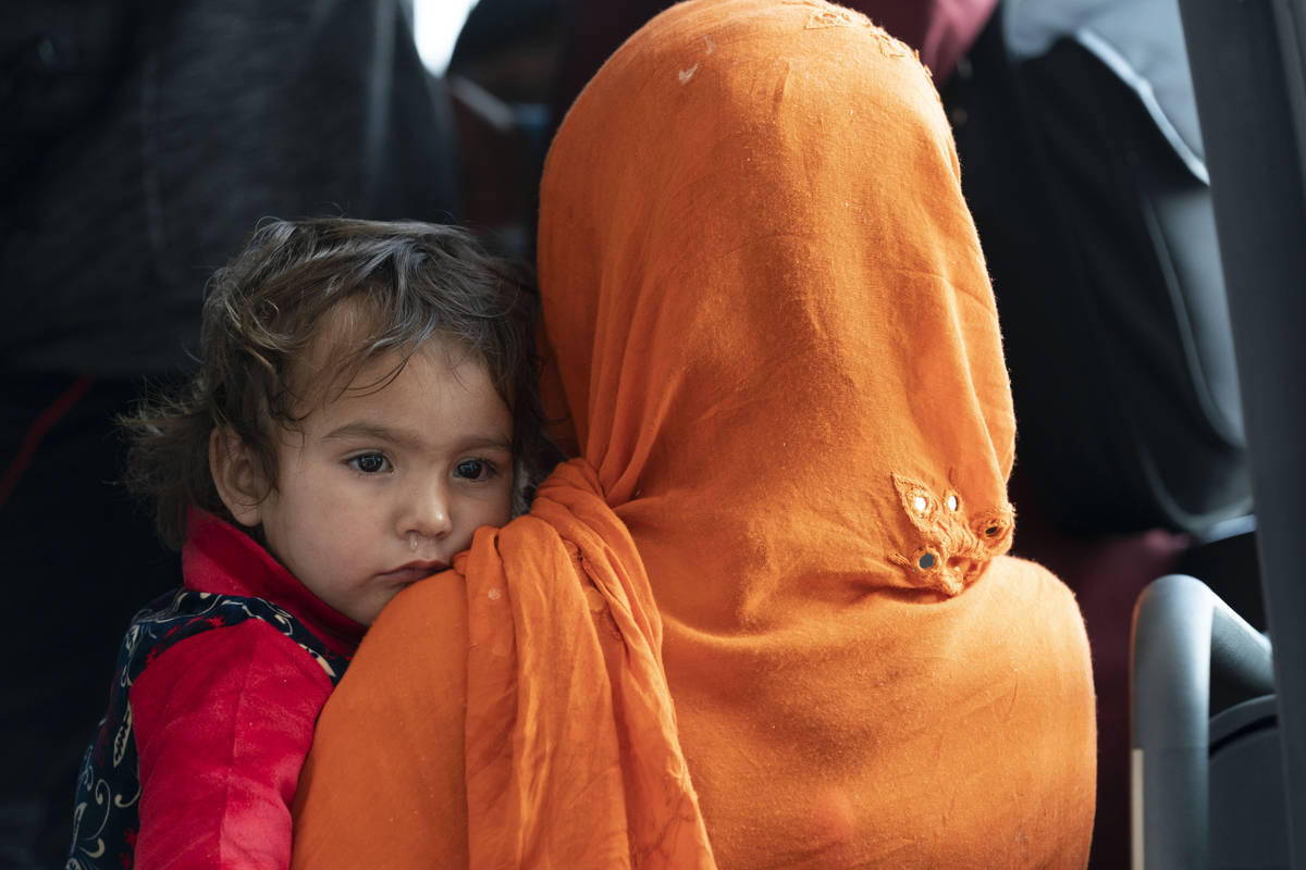Families evacuated from Kabul, Afghanistan, wait to board a bus after they arrived at Washingto ...