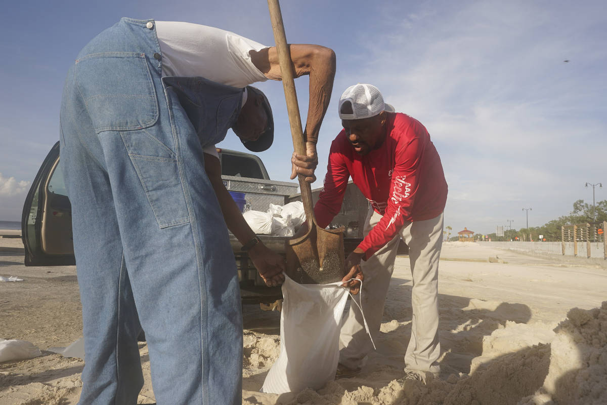 Gregory Moore, right, helps a local residents fill sand bags as they prepare for the expectd ar ...