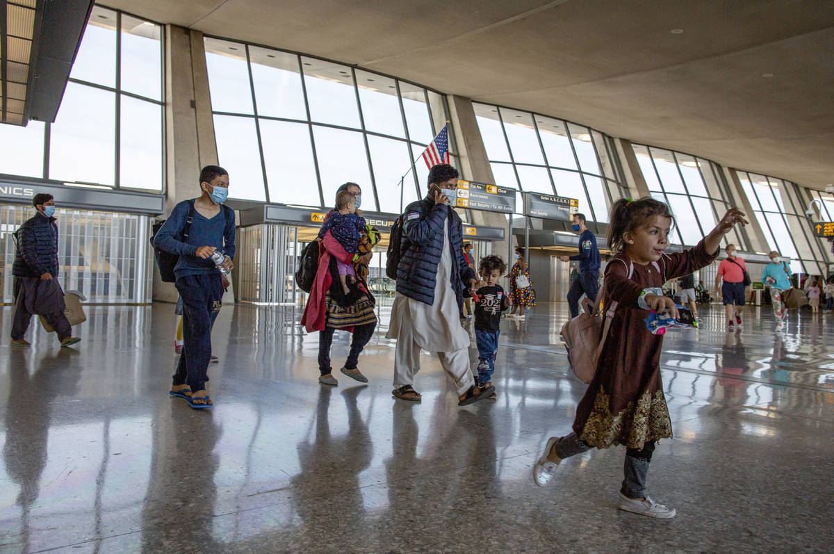 Families evacuated from Kabul, Afghanistan, walk through the terminal to board a bus after they ...