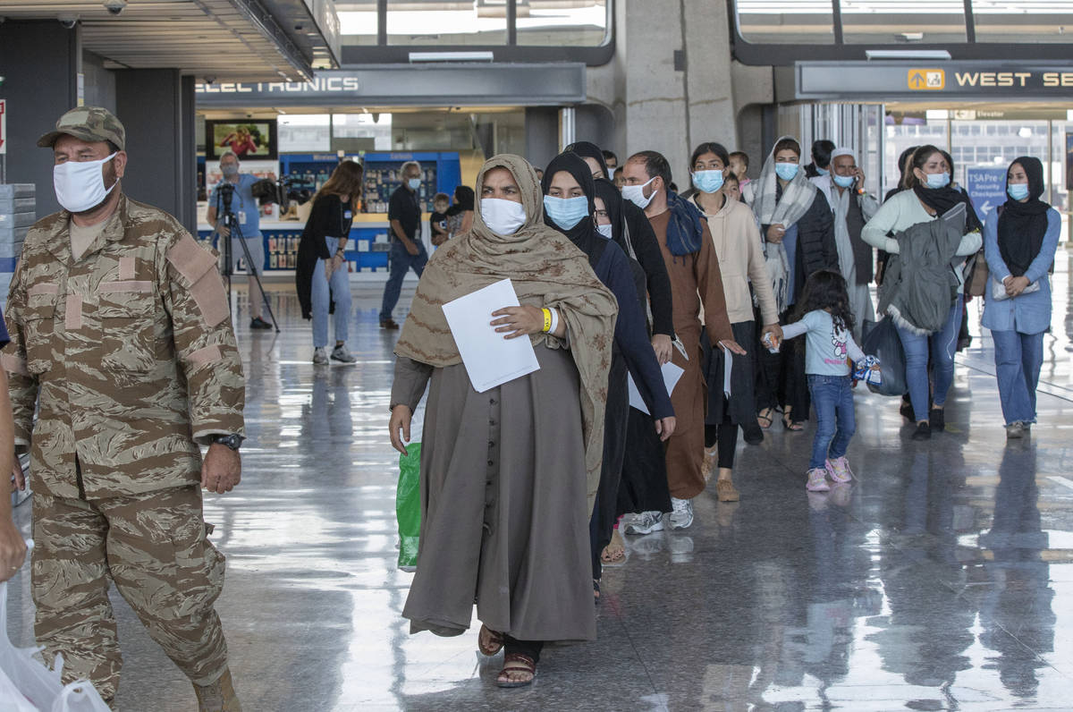 Families evacuated from Kabul, Afghanistan, walk through the terminal to board a bus after they ...