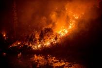 The Caldor Fire burns above the South Fork of the American River in the White Hall community of ...