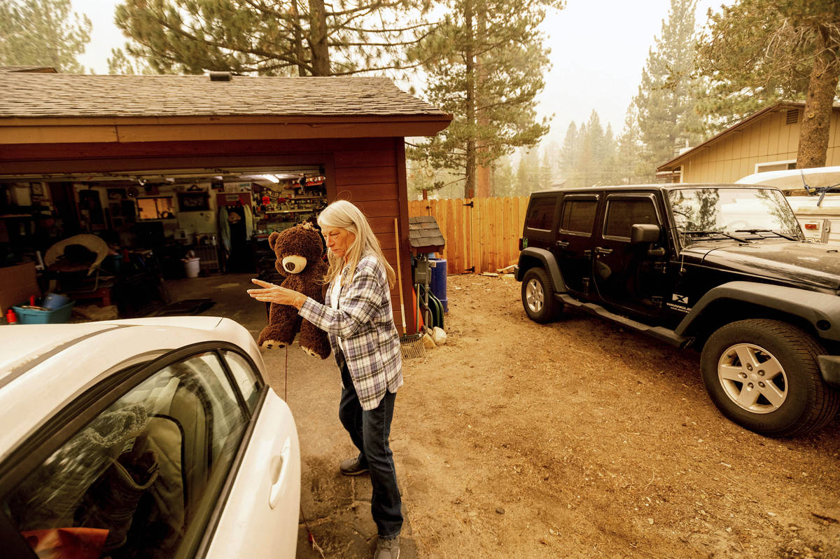 As the Caldor Fire approaches, Patty Kingsbury carries a teddy bear while evacuating from her S ...