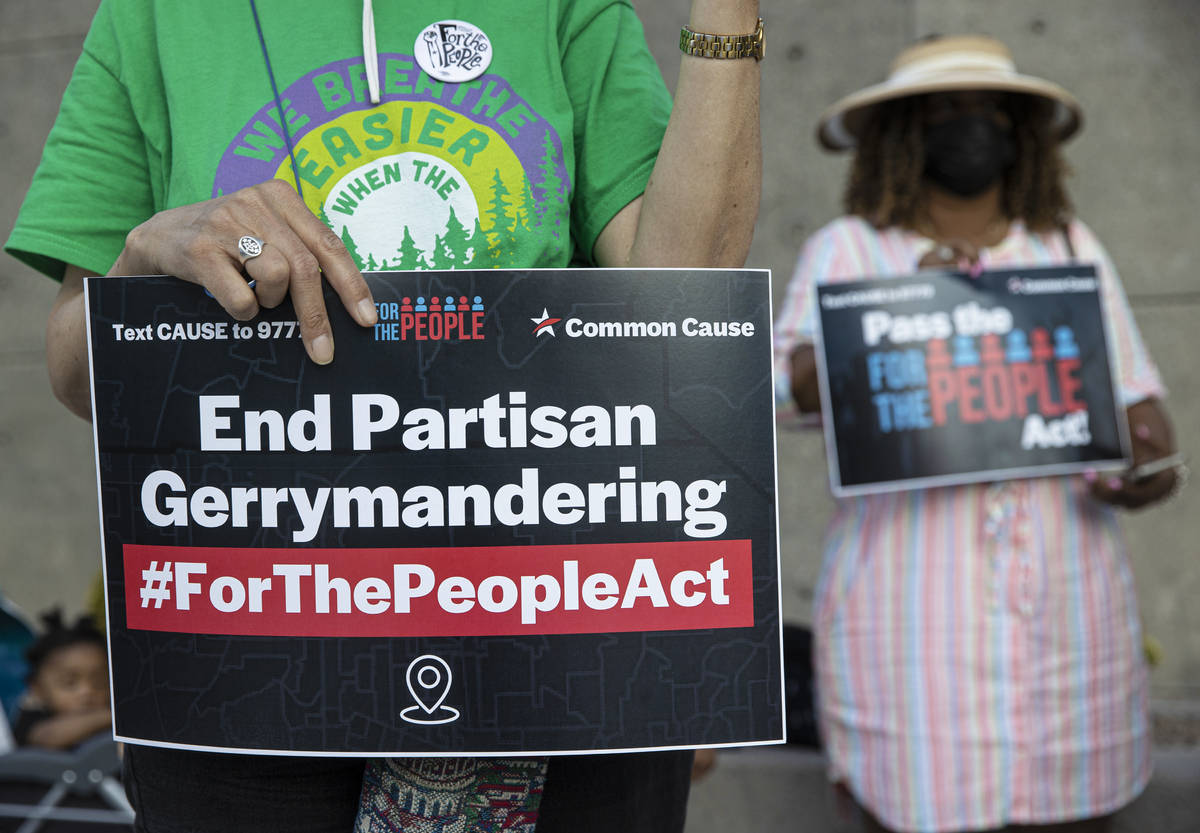 Demonstrators hold signs during an event against voter suppression sponsored by the NAACP and C ...