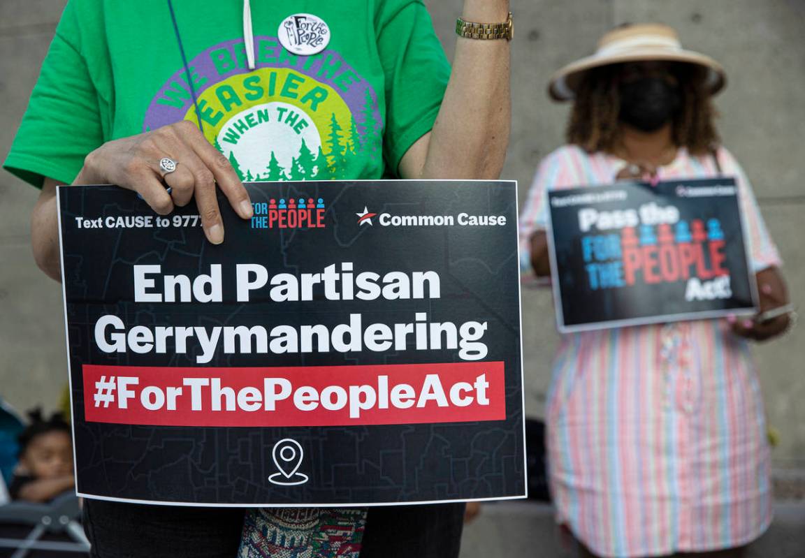 Demonstrators hold signs during an event against voter suppression sponsored by the NAACP and C ...