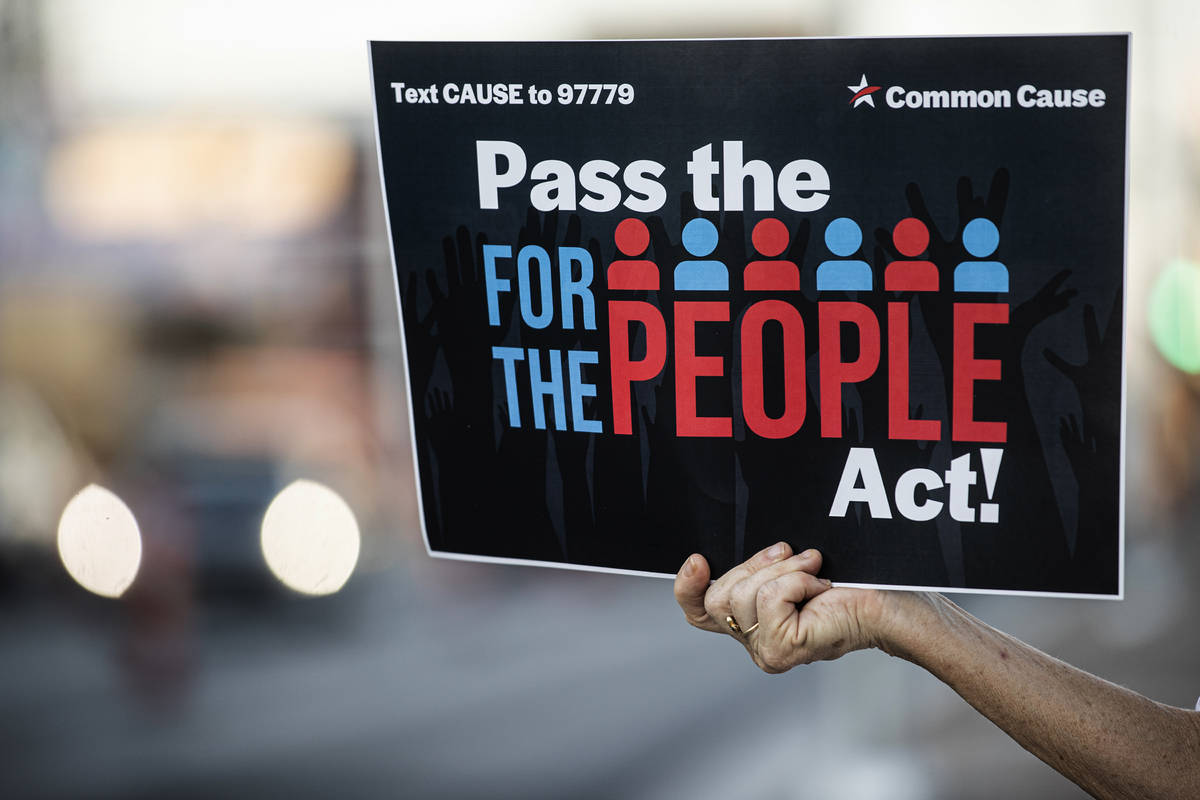 Demonstrators hold signs during an event against voter suppression sponsored by the NAACP and C ...