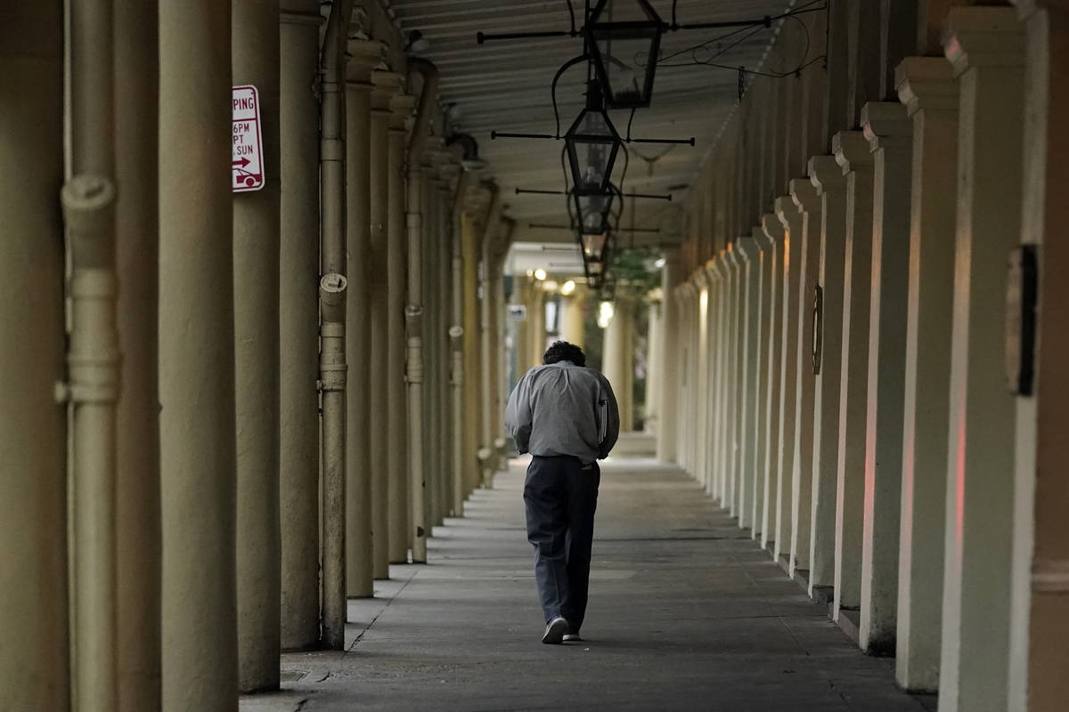 A man walks along businesses with protective boarding in the French Quarter as the early effect ...