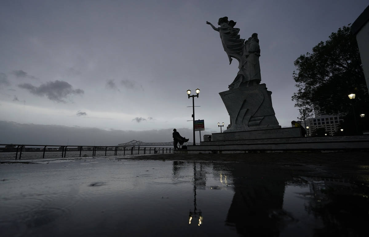 A man walks along the Mississippi River near the French Quarter as the sun rises and the early ...