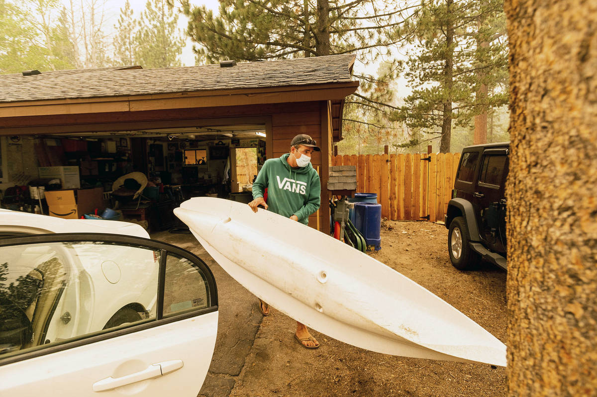As the Caldor Fire approaches, Greg Collard carries a kayak while helping family members evacua ...