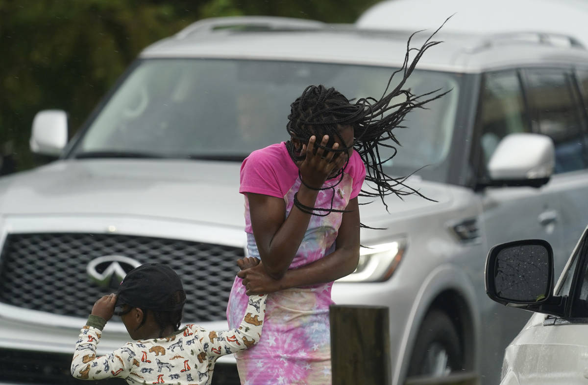 A young girl blocks her face from the wind and rain produced by Hurricane Ida, Sunday, Aug. 29, ...