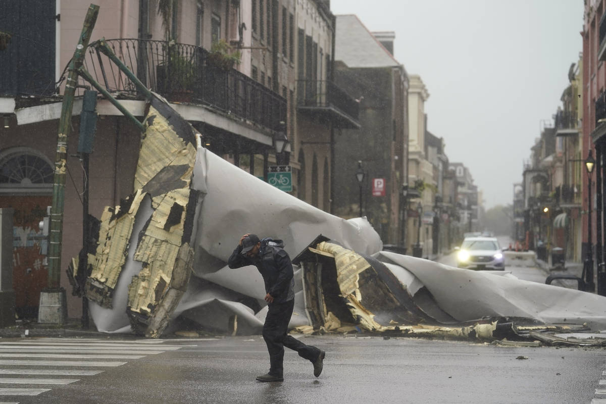 A man passes by a section of roof that was blown off of a building in the French Quarter by Hur ...