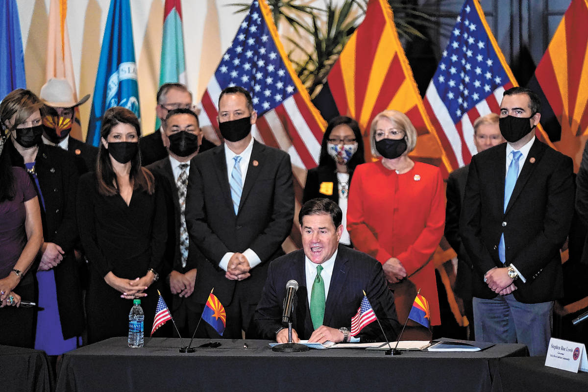 Surrounded by Arizona legislators, Republican Arizona Gov. Doug Ducey speaks at a bill signing ...