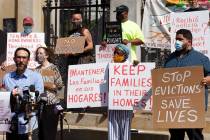 People from a coalition of housing justice groups hold signs protesting evictions during a news ...