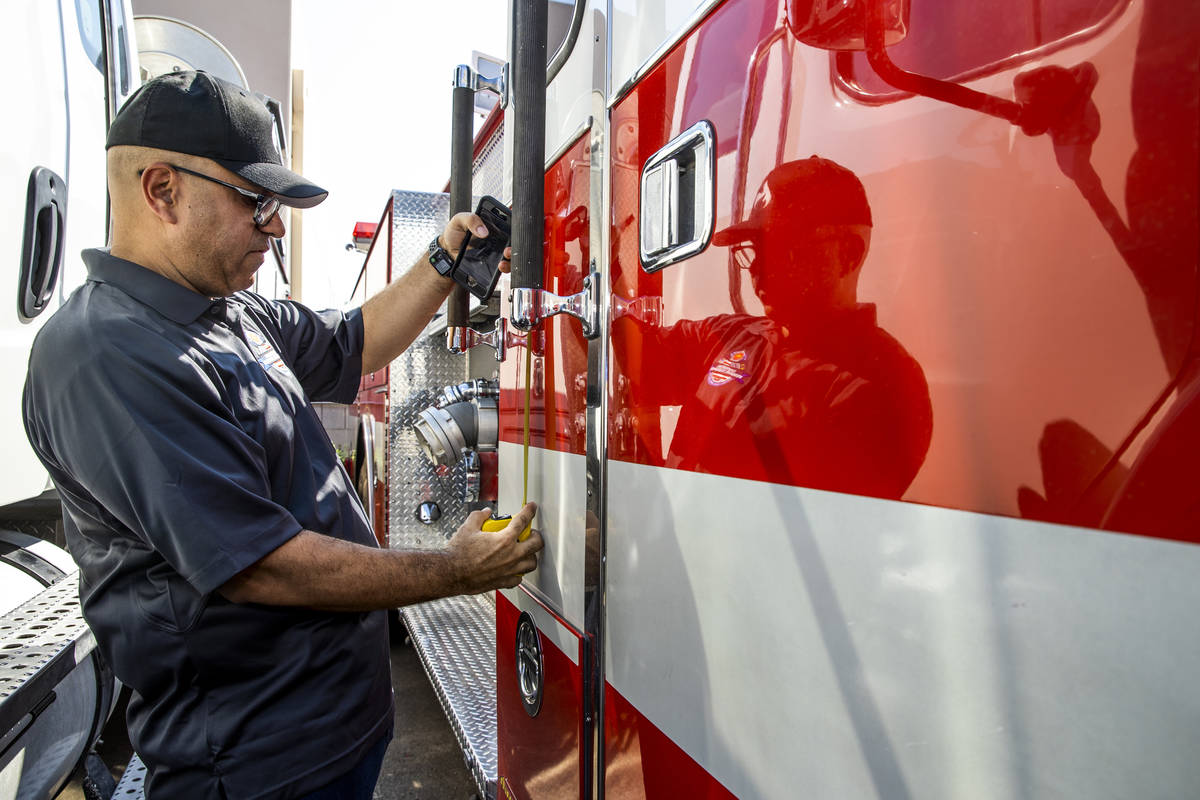 Frank Pizarro measures a space on the side of his 1991 Pierce firetruck which is undergoing res ...
