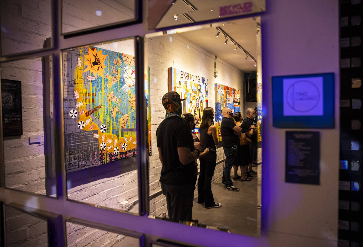 People, reflected in a mirror, watch a performer at Recycled Propaganda during First Friday in ...