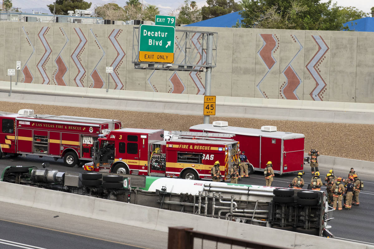 Emergency personnel work at the scene where a fuel tanker truck overturned on U.S. Highway 95 o ...